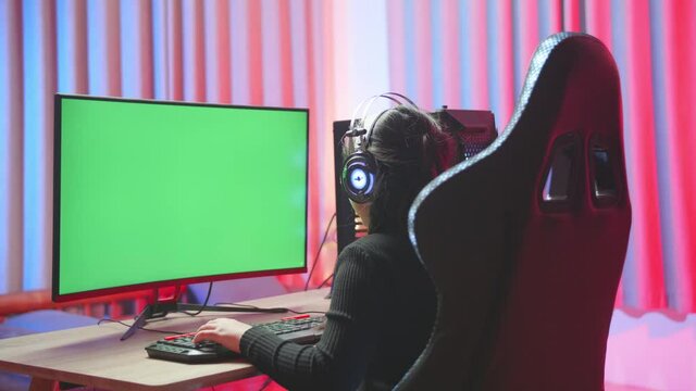 Young Girl Seating In Front Of The Computer While Playing Exited Computer Game With Green Screen Display
