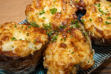 A selection of delicious Fish Pie Potato Skins topped with cheese and garnish on a wooden kitchen table background