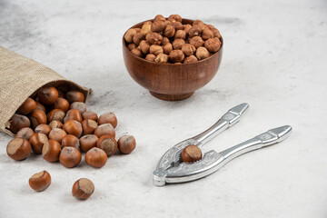 Organic shelled and kernels of hazelnuts in burlap with cracking tool