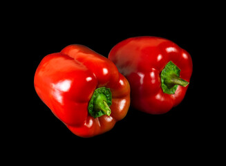 Two red bell peppers isolated on black background.