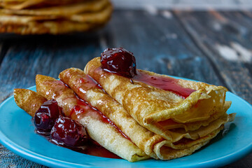 Fresh pancakes with cherry jam on a plate.