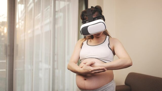 Asian pregnant woman raise children with virtual reality online tutorial technology at home, New family baby born concept.