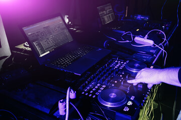 DJ mixing music on turntable console at in the night club