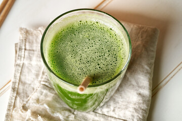 Green juice in a glass, with an ecological paper straw