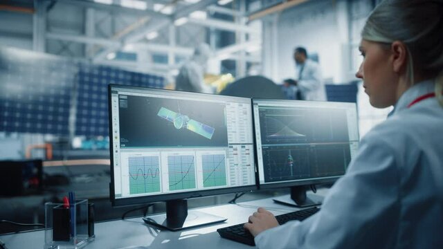 Female Engineer uses Computer to Analyse Satellite, Calculate Orbital Trajectory Tracking. Aerospace Agency International Space Mission: Scientists Working on Spacecraft Construction. Over Shoulder