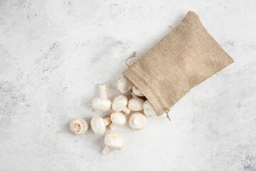 White mushrooms inside rustic baskets on marble background