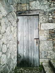 antique wooden door with a padlock in the stone wall. Fragment of ancient architecture