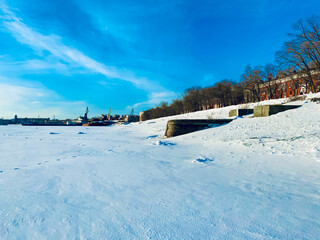 landscape with snow covered trees , ships in port and frozen river