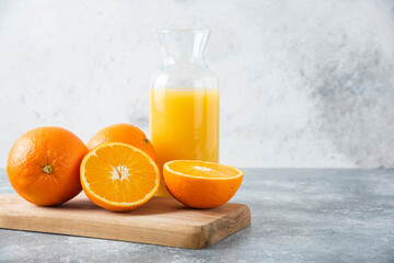 Glass pitcher of juice with sliced orange fruit on a wooden board