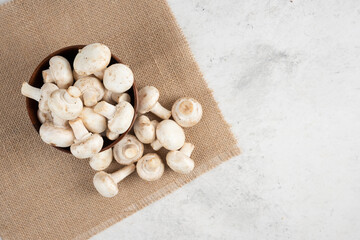 White mushrooms in a wooden cup on a piece of burlap