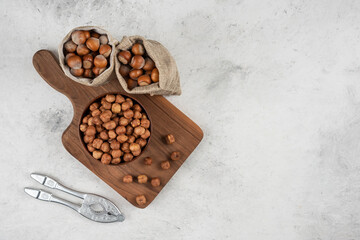 Bowl of organic hazelnut kernels on cutting board with shelled hazelnuts