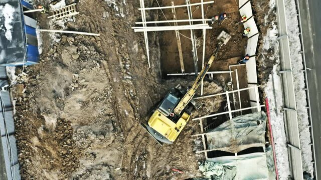 Aerial Overhead Shot Of An Excavator And Unknown Workers On A Construction Site