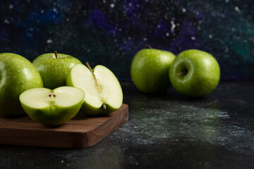 Whole and sliced ripe green apples on wooden board