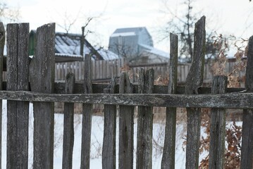 Fototapeta na wymiar gray broken wooden plank wall fence a rural street