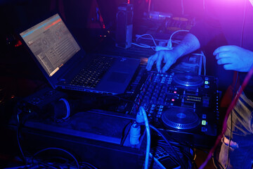 DJ mixing music on turntable console at in the night club