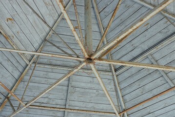 the inside of the old barn roof made of brown iron structure and gray wooden planks in the wall