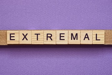 brown word extremal in small square wooden letters with black font on a lilac background