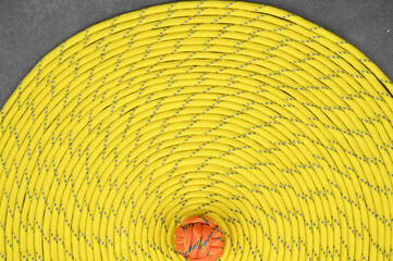 Yellow paracord, coiled in a tight spiral. The center of the spiral is shifted towards the bottom of the image.