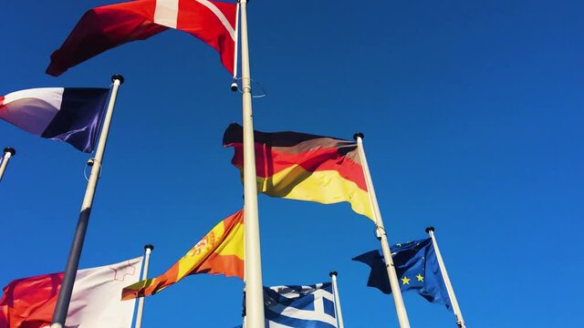 Waving flags against blue sky: Denmark, Germany, Spain, France, Greece, Malta, European Union.