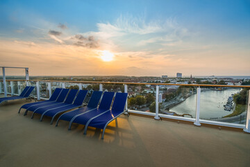 Upper deck of a cruise ship at sunset as it overlooks the Warnemunde Rostock port and coastal town along the Baltic sea of Northern Germany.