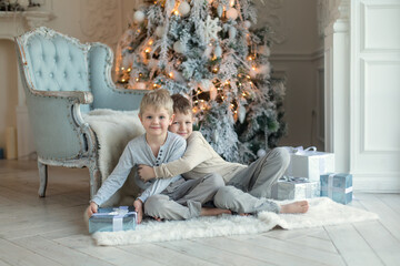 Two little brothers are playing and laughing near the Christmas tree . Family New Year unpacking gifts
