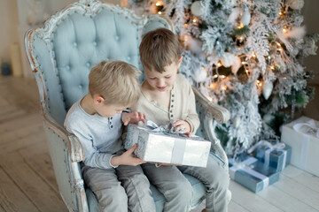 Two little brothers are playing and laughing near the Christmas tree . Family New Year unpacking gifts