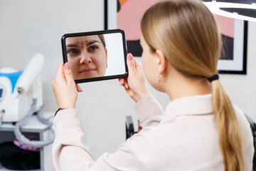 Makeup artist applies eyebrow tint for the permanent makeup of a young girl. Professional make-up and cosmetic face care