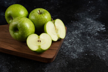 Whole and sliced ripe green apples on wooden board