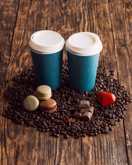Fototapeta na wymiar two paper cups of coffee, macaroons, beans, heart on wooden backgroun
