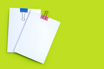 Stacking of business document with colorful binder clips on green background.