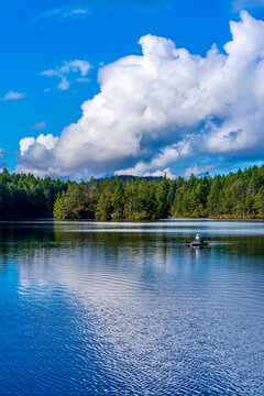 Fisherman on Thetis lake with reflective sky, Greater Victoria, British Columbia, Canada 