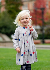 portrait of a little girl in grey dress fooling and walking around in a city