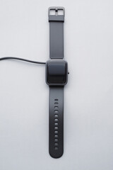 Fototapeta premium Black Smartwatch Charging from Wire Charger.