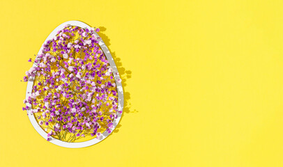 2021 Easter composition with egg shaped white frame and purple and violet flowers on illuminating background. Minimal holiday concept with copy space.