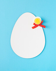 2021 Easter unique composition made of white egg shape, peace of boiled egg and red ribbon. Vertical pastel blue background. Flat lay.