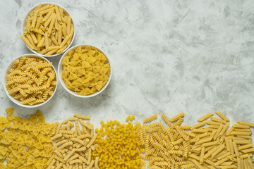 Assortment of Italian pasta on grey background with copy space, flat lay.