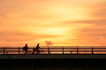 bicycle crossing the bridge.   &ldquo;Golden hour&rdquo; dim light sky.  blurred focus silhouette image. Japan・tokyo. 