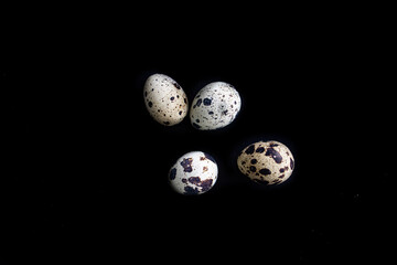 little quail eggs on a bright smooth black background in close-up