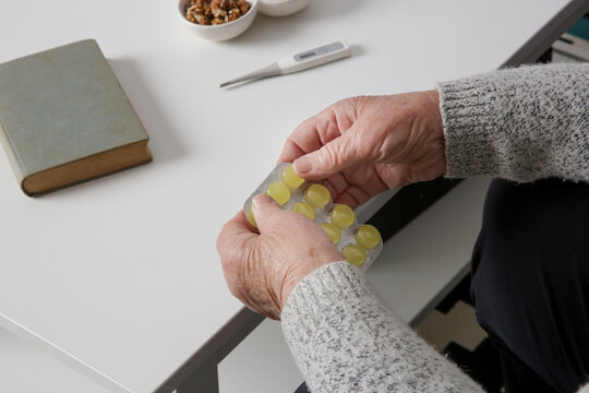 Image of elderly woman's hands holding pills above white table