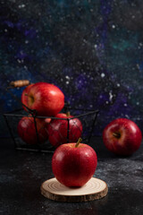 Red whole apples in metal basket on dark background