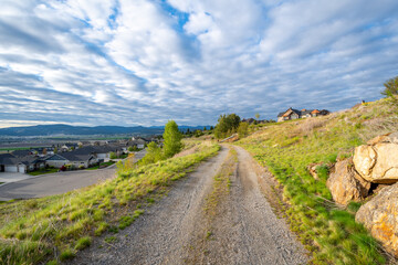 A dirt road path across a trail above the valley and city of Liberty Lake, Washington, a suburb of...