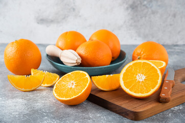 Sliced orange fruits with whole oranges on a wooden board