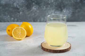 A glass cup of fresh lemon juice on a wooden board