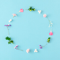 Creative spring layout made of colorful flowers, leaves and pearls on pastel blue background with copy space. Nature background. Flat lay.