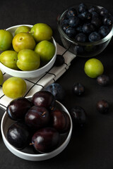 Black and green plums in white ceramic saucer in the kitchen