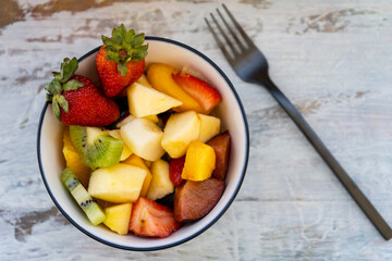 Natural and healthy fruit salad with orange set in a bowl on a rustic surface. Healthy Food Concept, Healthy Life.