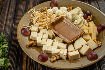 Cheese assortment plate on dark wooden background, free space. Top view on plate with snack on for wine with honey on round catering platter
