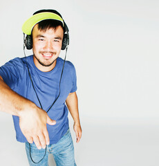 young asian man in hat and headphones listening music on white background