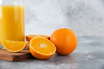 Glass pitcher of juice with fresh orange fruits on a wooden board