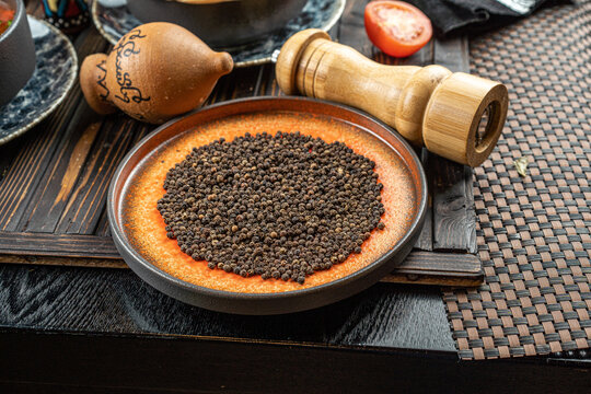 Heap of hot black pepper in bowl on a wooden table © suvorovalex